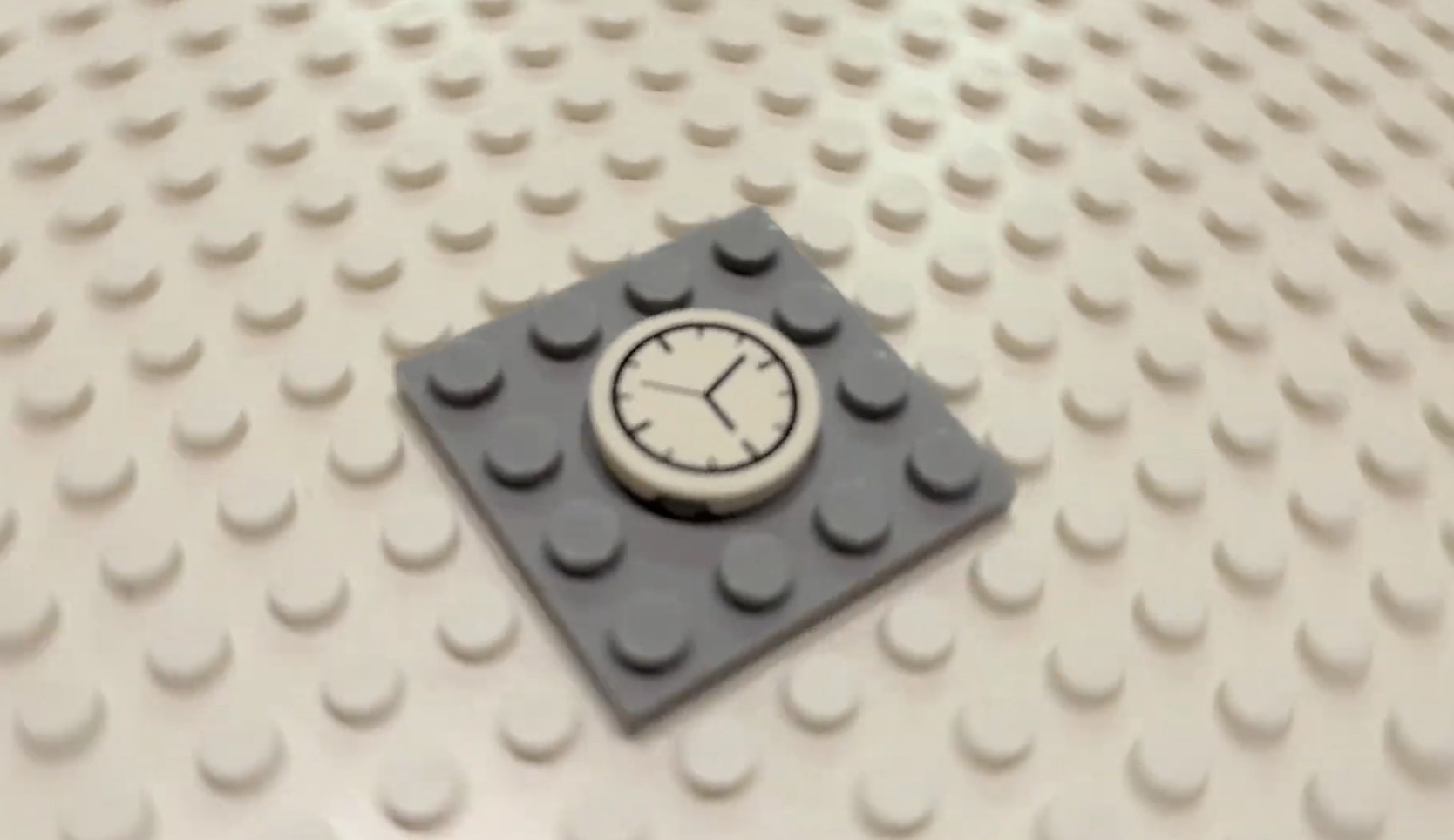 A small LEGO clock tile on a gray plate, set on a light LEGO baseplate